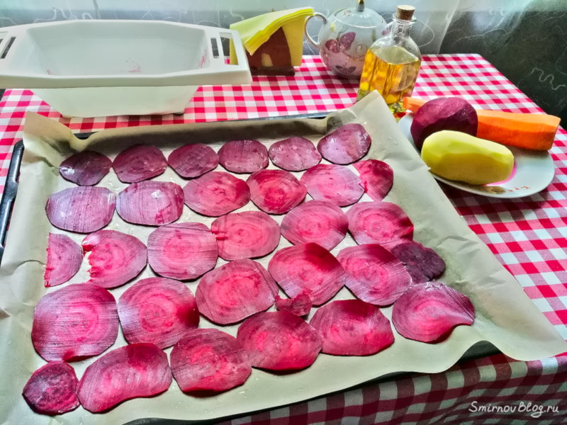 Тонкие ломтики свежей свеклы на противне для приготовления домашних чипсов в духовке