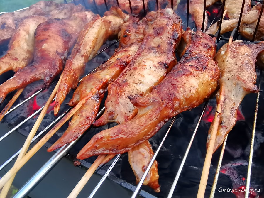 Куриные крылышки жарятся на огне на решётке