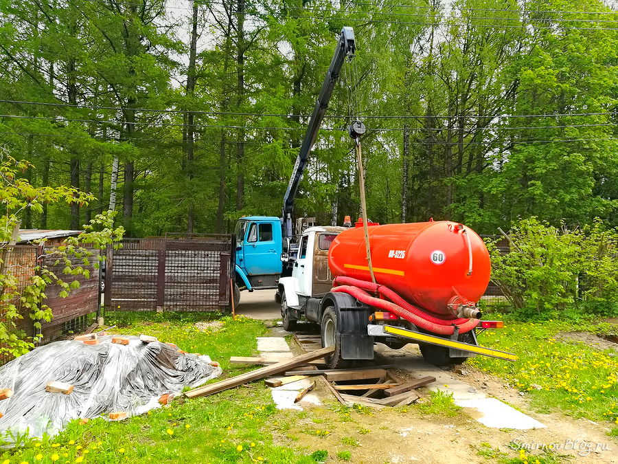 Манипулятор вытаскивает из ямы ассенизаторский грузовик